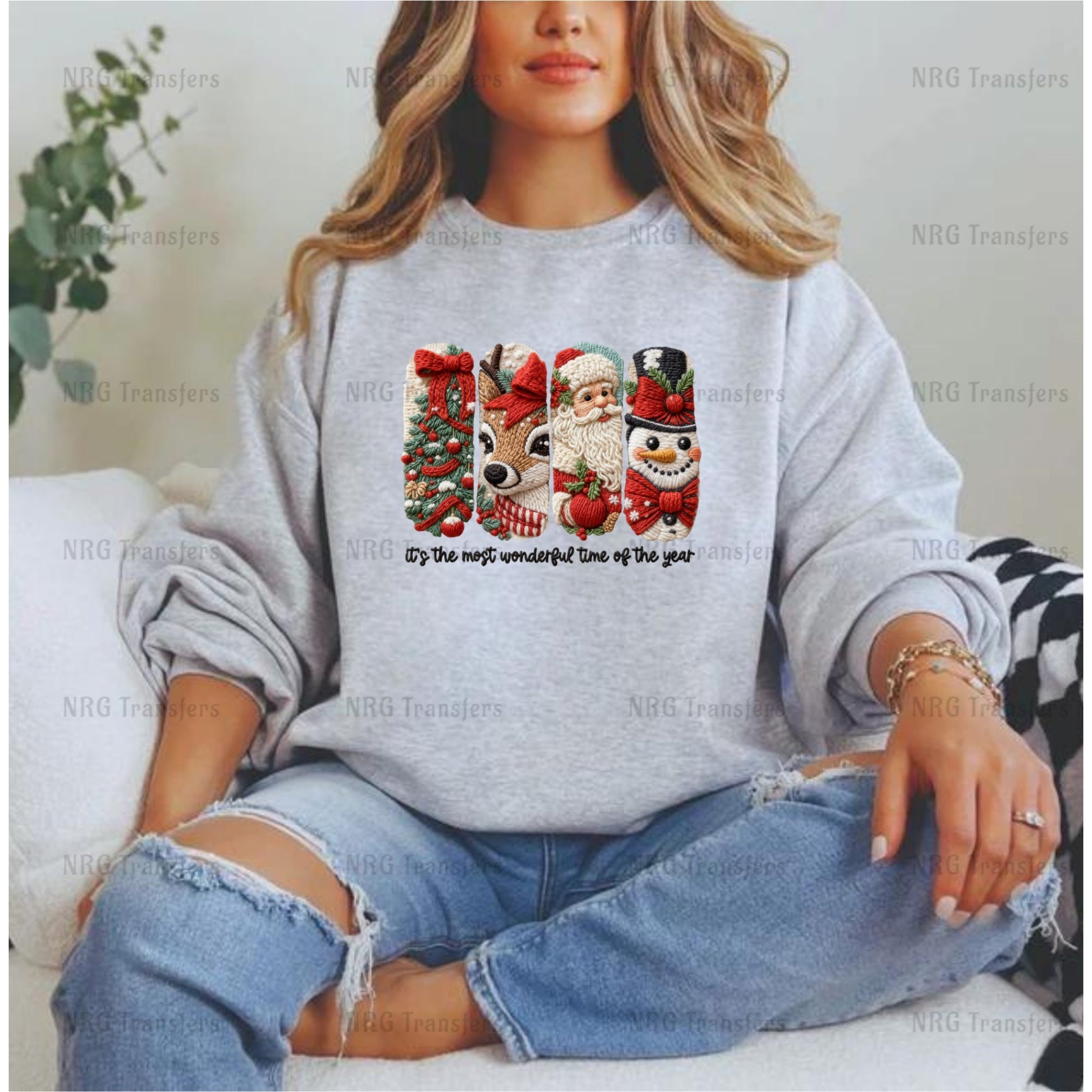 A woman wearing a gray sweatshirt with a Christmas-themed graphic design featuring Santa Claus, a reindeer, and a snowman.