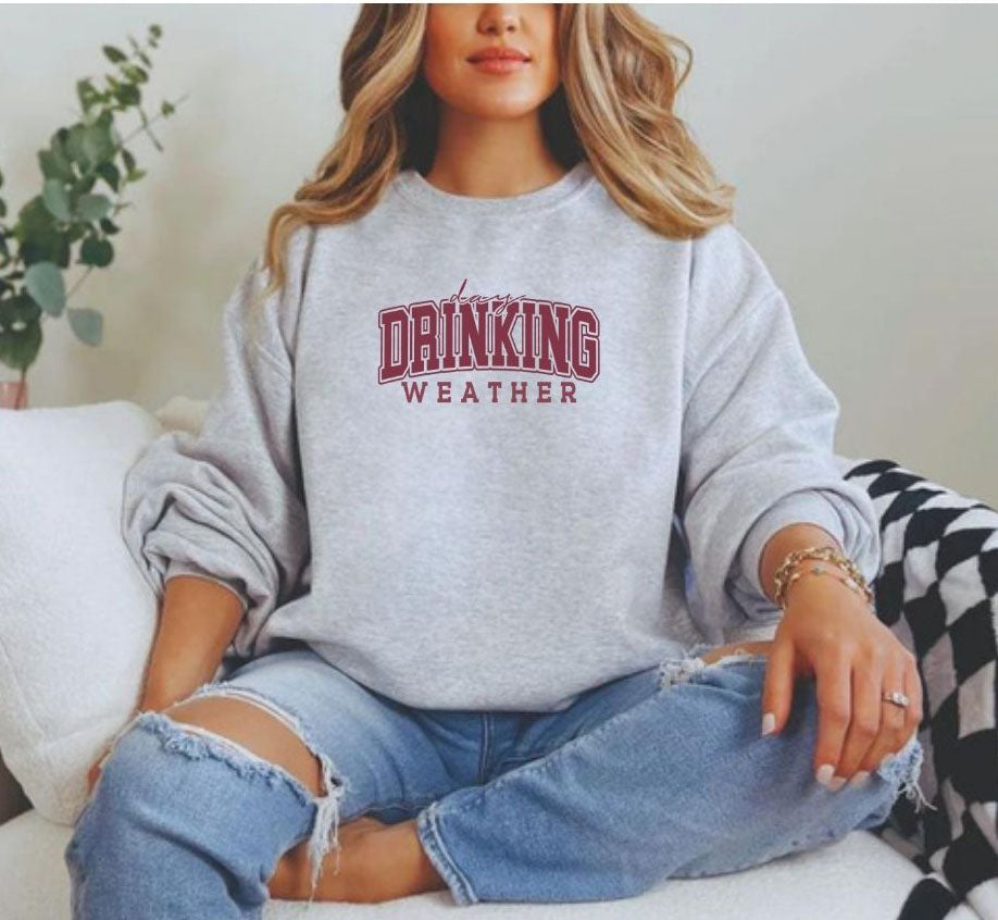 a woman sitting on a couch wearing a drinking sweatshirt