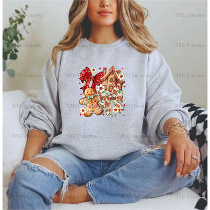 A woman wearing a gray sweatshirt with a graphic design of a gingerbread house and a red bow on it.