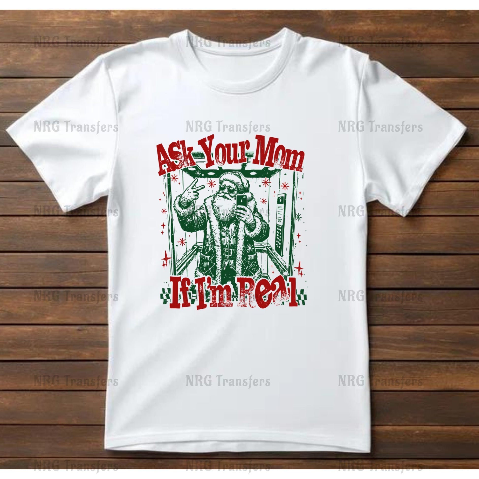A white t-shirt with a graphic design featuring a Santa Claus figure and the text "Ask Your Mom If I'm Real" in red and green colors.
