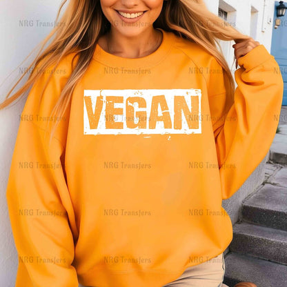 a woman wearing an orange sweatshirt with the word vegan printed on it