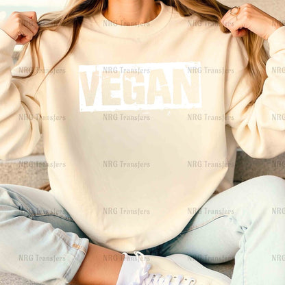 a woman sitting on a couch wearing a sweatshirt with the word vegan on it